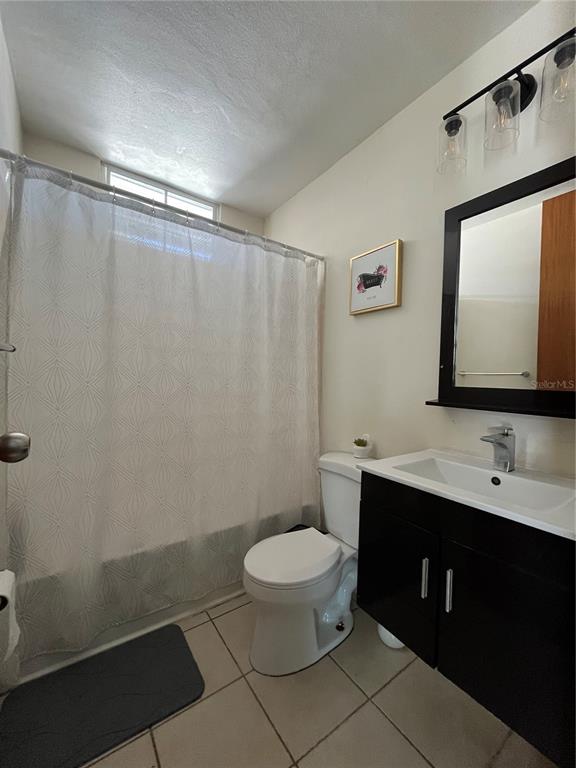 A bathroom features a shower with a white curtain, a toilet, and a black vanity — Urb. Arboleda CALLE COROZO UNIT B 18, HUMACAO, PR