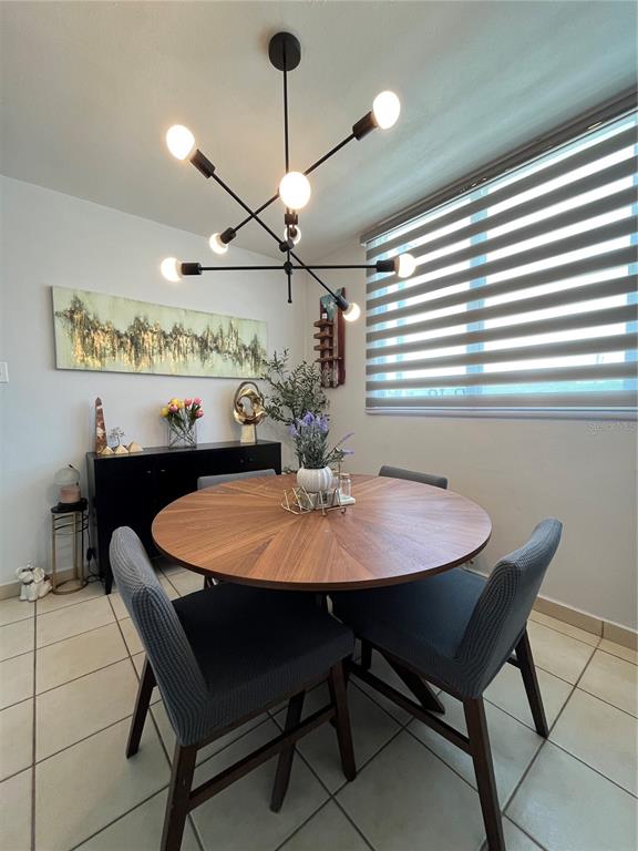 A dining room features a round wooden table, four gray chairs, and a modern chandelier — Urb. Arboleda CALLE COROZO UNIT B 18, HUMACAO, PR