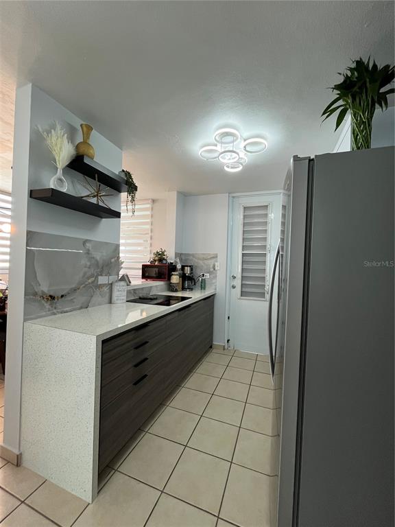 A modern kitchen features dark wood cabinetry, white quartz countertops, and a unique ceiling light — Urb. Arboleda CALLE COROZO UNIT B 18, HUMACAO, PR