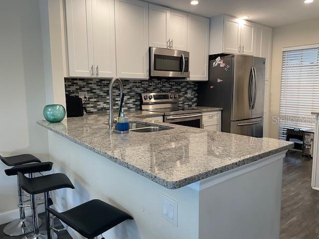 A kitchen features white cabinetry, granite countertops, stainless steel appliances, and a breakfast bar — 5112 BAYSHORE BOULEVARD, TAMPA, FL
