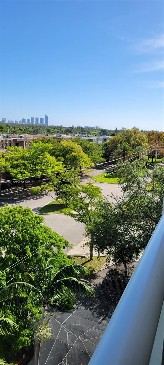 An elevated view shows a suburban street with lush trees and distant city skyline buildings — 13499 Biscayne Blvd # 511, North Miami FL 33181, NORTH MIAMI, FL