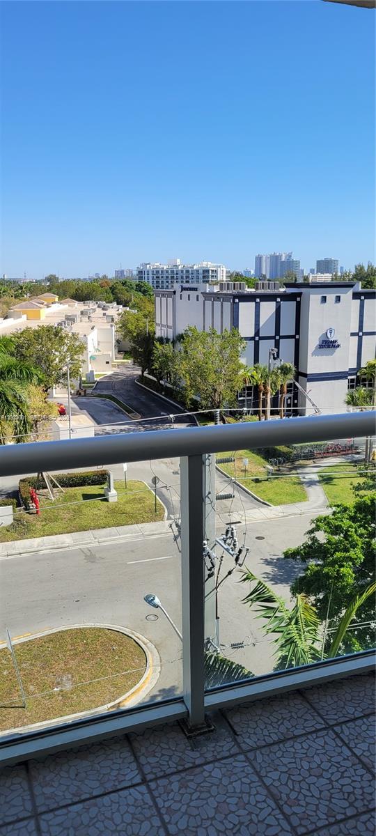 An elevated view from a balcony overlooking a street, trees, and a storage facility — 13499 Biscayne Blvd # 511, North Miami FL 33181, NORTH MIAMI, FL