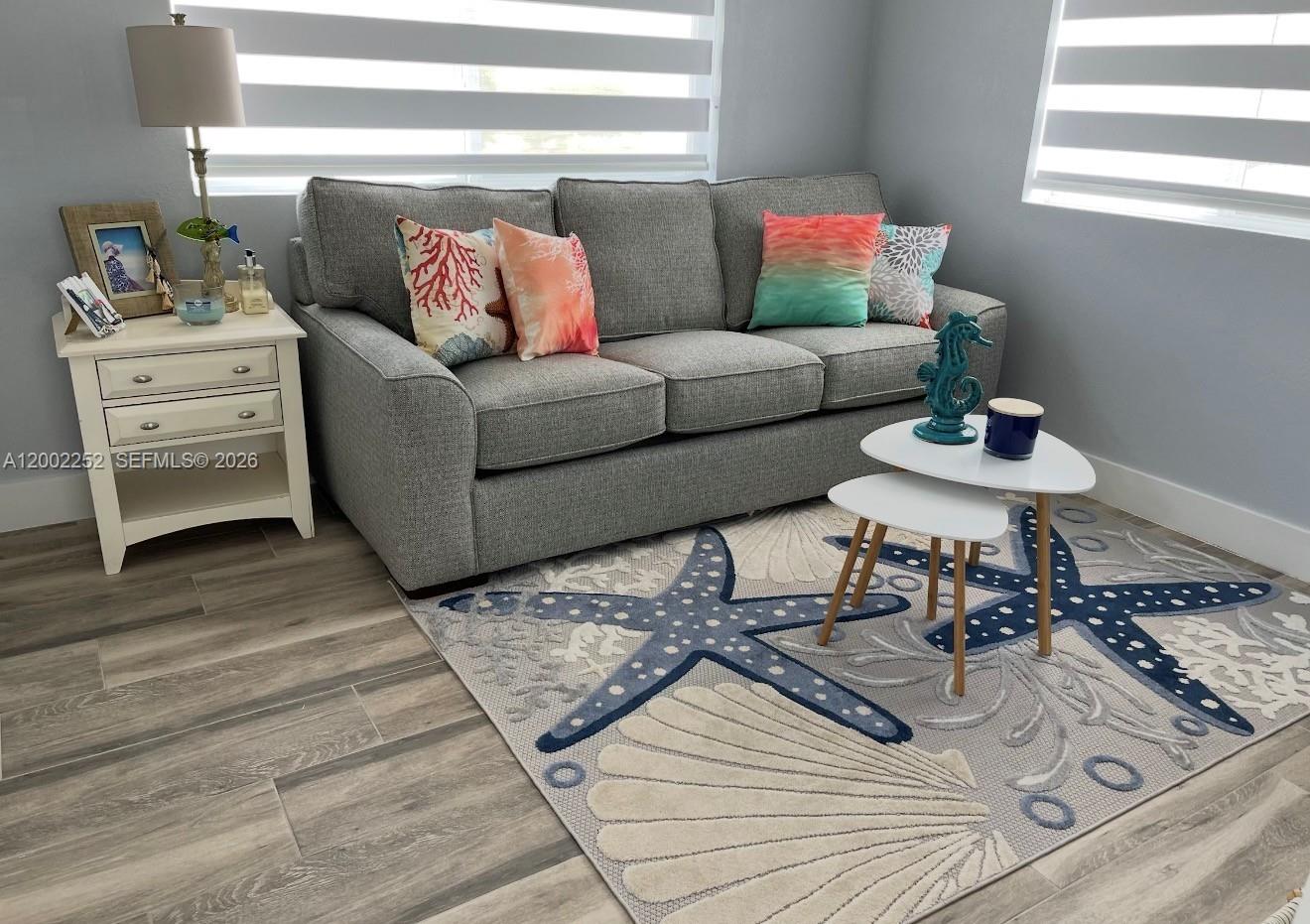 A living room features a gray sofa, a coastal-themed rug, and a white side table — 94825 Overseas Hwy 100, Key Largo FL 33037, KEY LARGO, FL