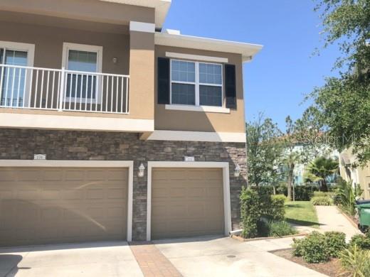 A two-story townhouse with three garage doors, a second-floor balcony, and two parked cars — 7001 INTERBAY BOULEVARD UNIT 235, TAMPA, FL