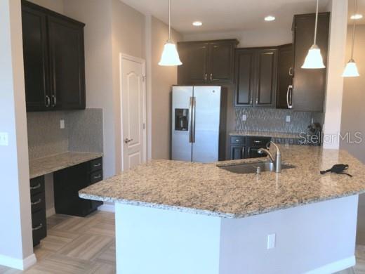 A kitchen with dark cabinets and granite countertops opens to a dining area with tile flooring — 7001 INTERBAY BOULEVARD UNIT 235, TAMPA, FL