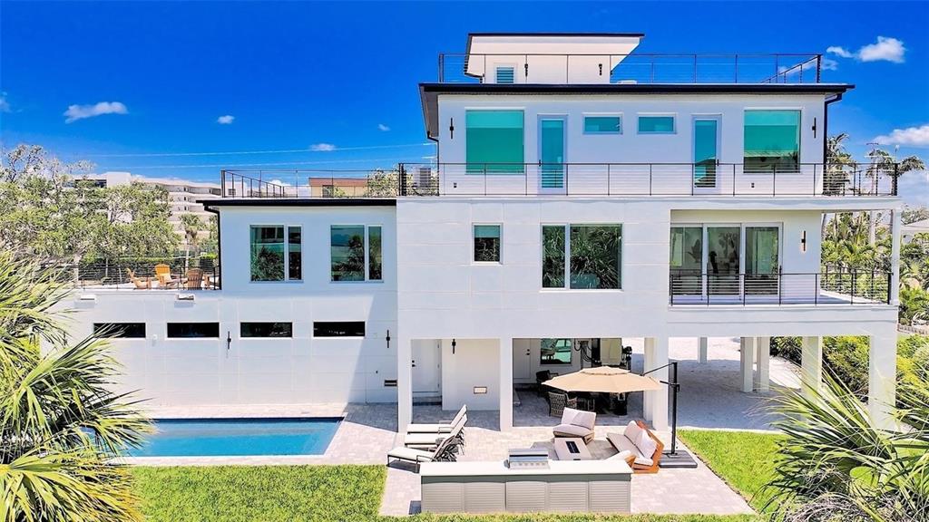 A modern three-story white house features a swimming pool, patio, and elevated balconies — 8800 MIDNIGHT PASS ROAD, SARASOTA, FL
