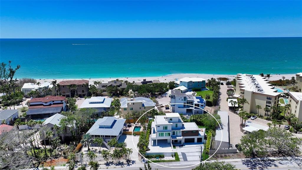 An aerial view shows a modern multi-story house with a flat roof near the beach — 8800 MIDNIGHT PASS ROAD, SARASOTA, FL