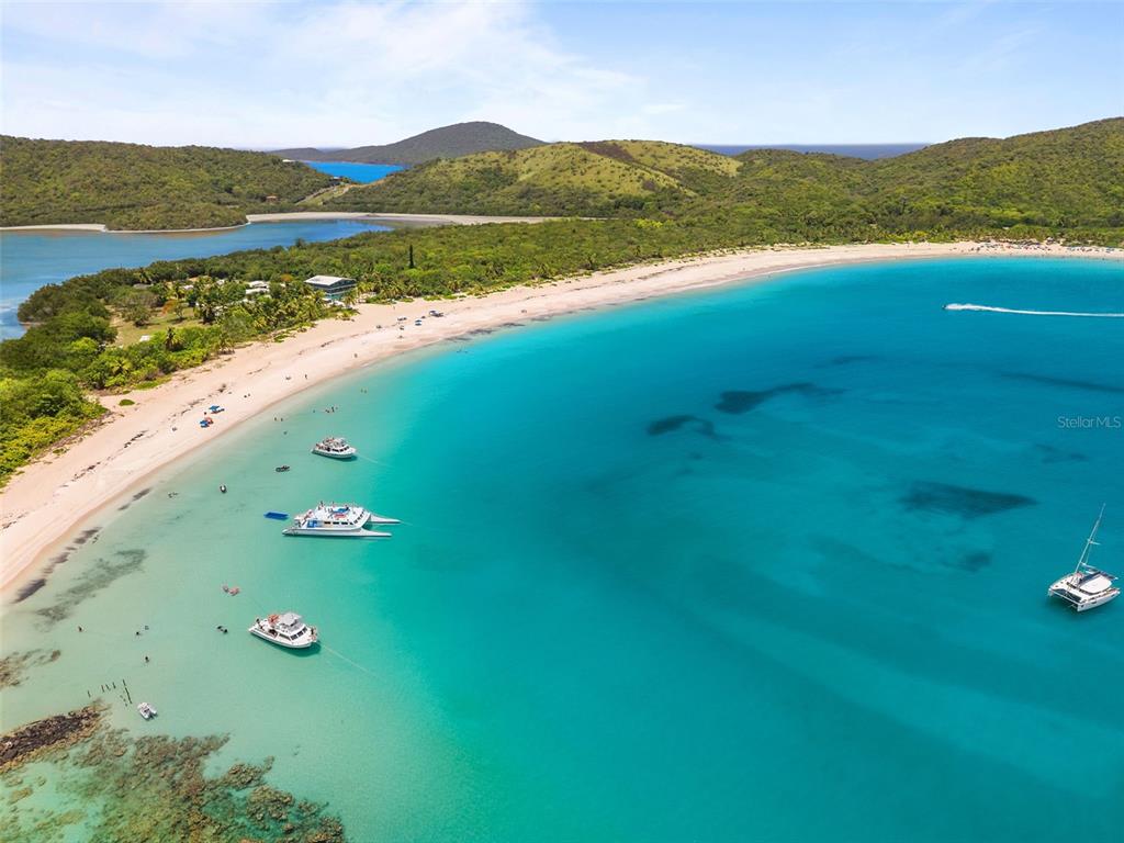 A white wooden balcony railing overlooks a lush green landscape and a blue bay — 1 SEABOURNE, CULEBRA, PR