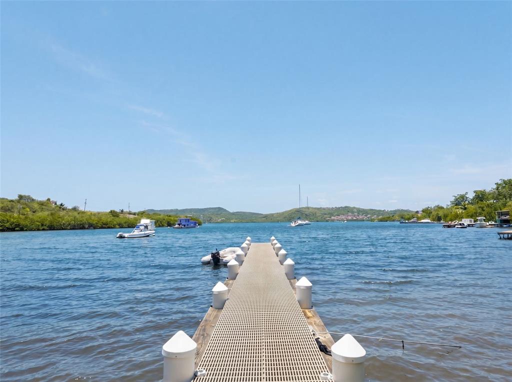 A long metal pier extends into a calm bay with several boats in the distance — 1 SEABOURNE, CULEBRA, PR