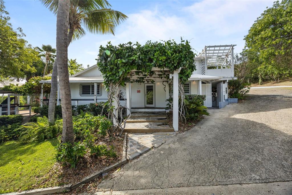 A white house features a vine-covered pergola over the entrance and a concrete driveway — 1 SEABOURNE, CULEBRA, PR