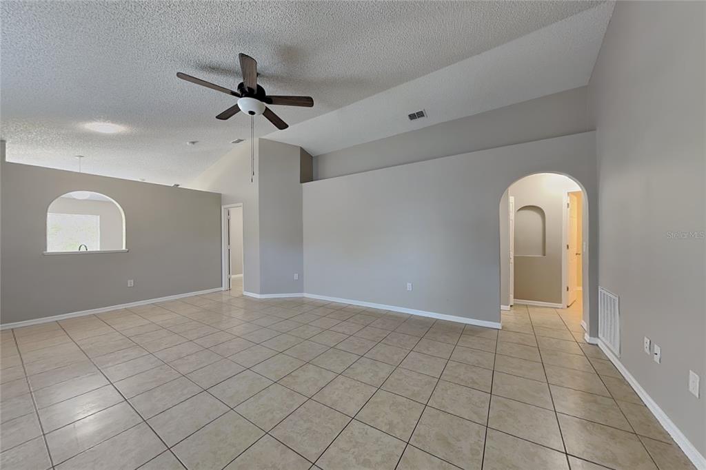 An empty living room features vaulted ceilings, tile flooring, and two arched wall cutouts — 11621 IVY FLOWER LOOP, RIVERVIEW, FL
