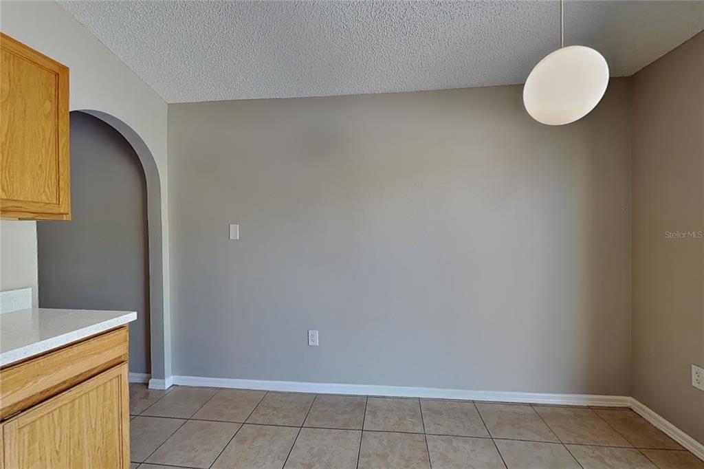A dining area with tile flooring, a light fixture, and an arched doorway — 11621 IVY FLOWER LOOP, RIVERVIEW, FL