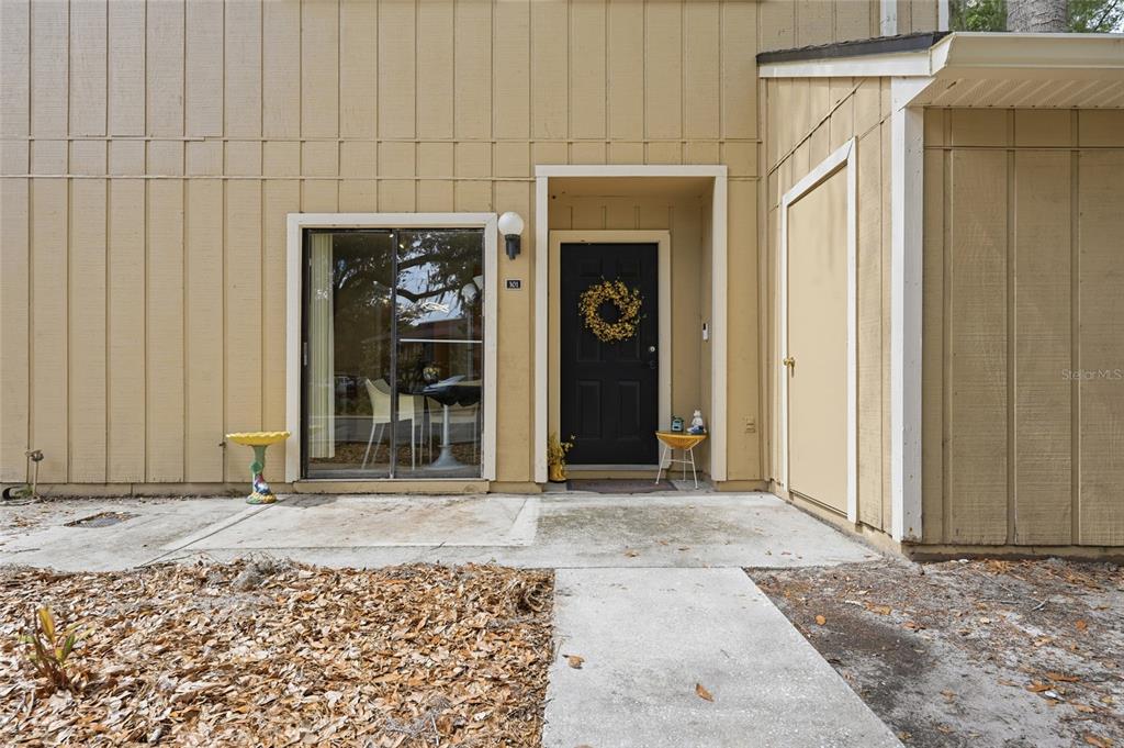 The exterior of a tan building features a black front door and a sliding glass door — 507 NW 39TH ROAD UNIT 301, GAINESVILLE, FL