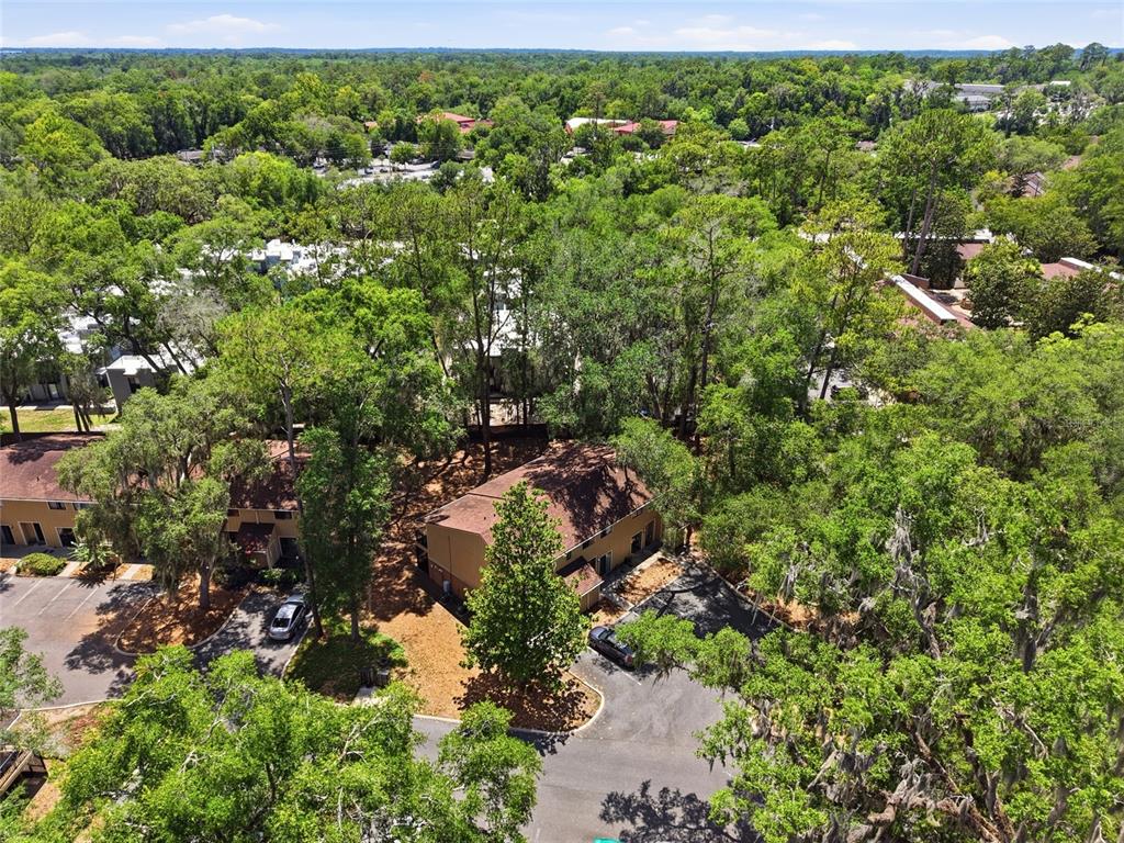 An aerial view shows two multi-story residential buildings surrounded by dense trees and parking lots — 507 NW 39TH ROAD UNIT 301, GAINESVILLE, FL