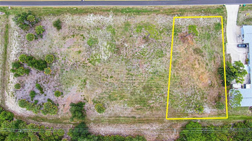 An aerial view shows a rectangular vacant lot outlined in yellow next to a driveway — 223 BOUNDARY BOULEVARD, ROTONDA WEST, FL