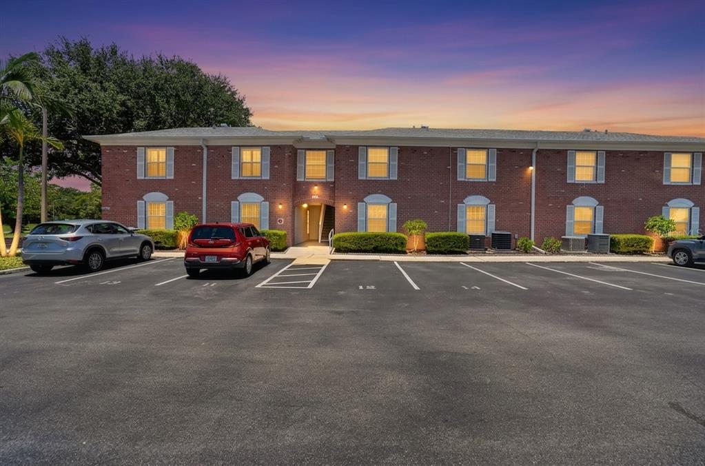 A two-story brick apartment building with a parking lot in the foreground at sunset — 3595 40TH AVENUE S UNIT 2, ST PETERSBURG, FL