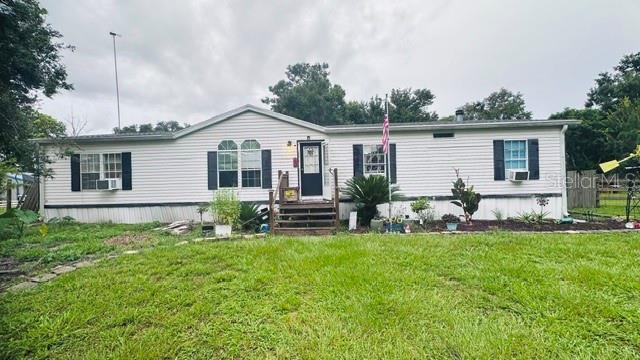 A single-story manufactured home with white siding, a front porch, and a grassy yard — 446 QUAIL STREET, LADY LAKE, FL