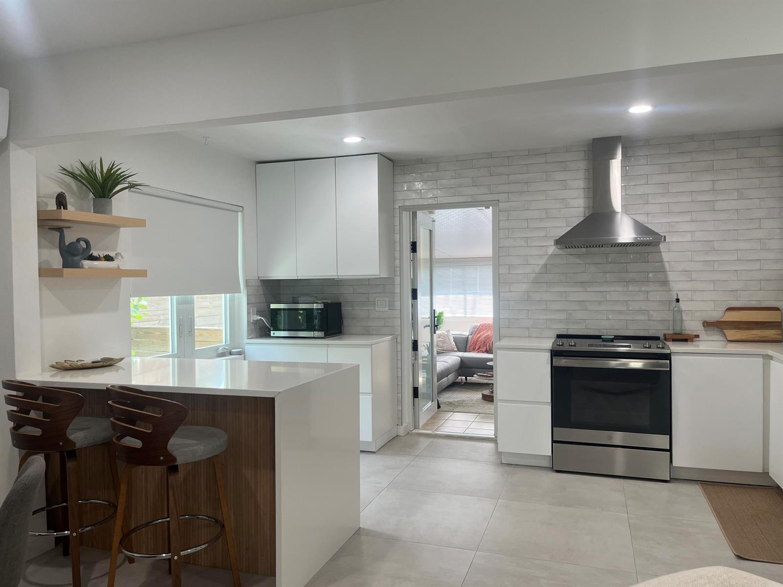 A modern kitchen features white cabinetry, a waterfall island, stainless steel appliances, and subway tile — 1612 N N Street, FL 33460, FL