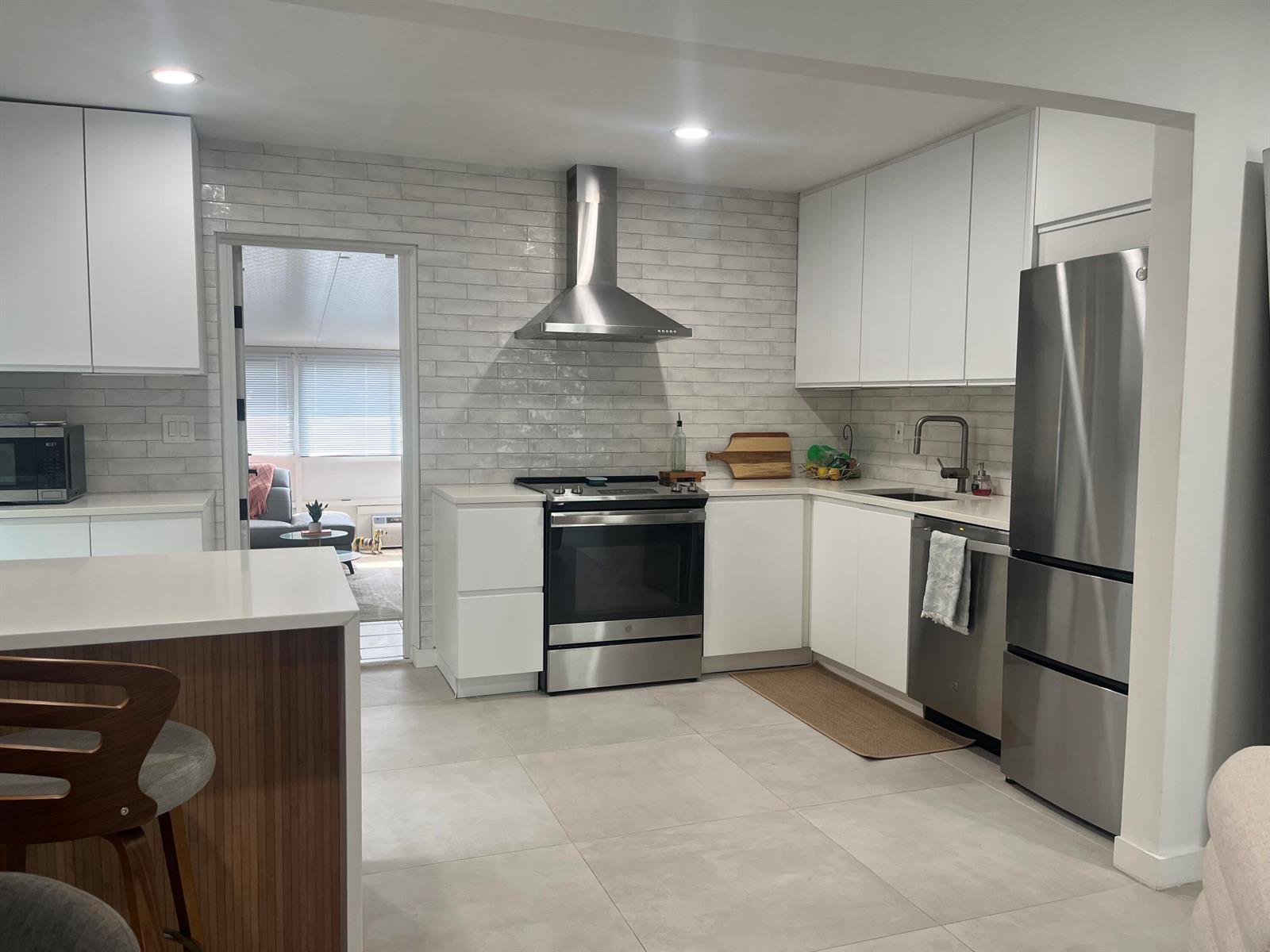 A modern kitchen features white cabinets, stainless steel appliances, and light gray subway tile backsplash — 1612 N N Street, FL 33460, FL