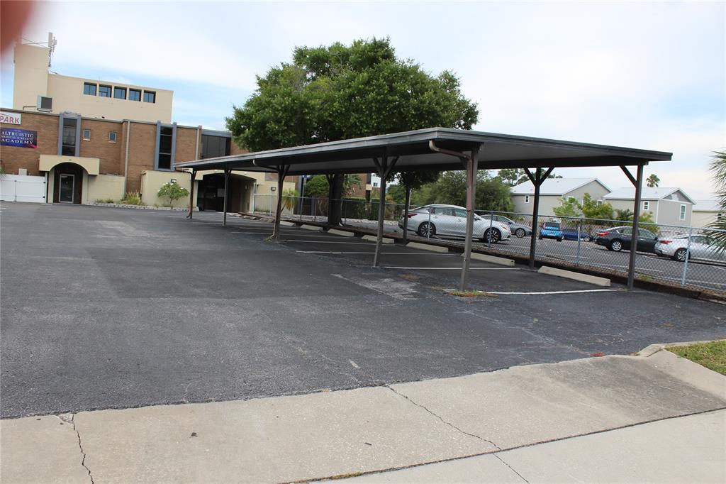 An outdoor parking lot features a metal carport structure next to a multi-story brick building — 1253/1255 PARK STREET, CLEARWATER, FL