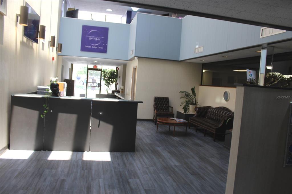 A reception area features a dark desk, wood-look flooring, and a seating area with leather furniture — 1253/1255 PARK STREET, CLEARWATER, FL