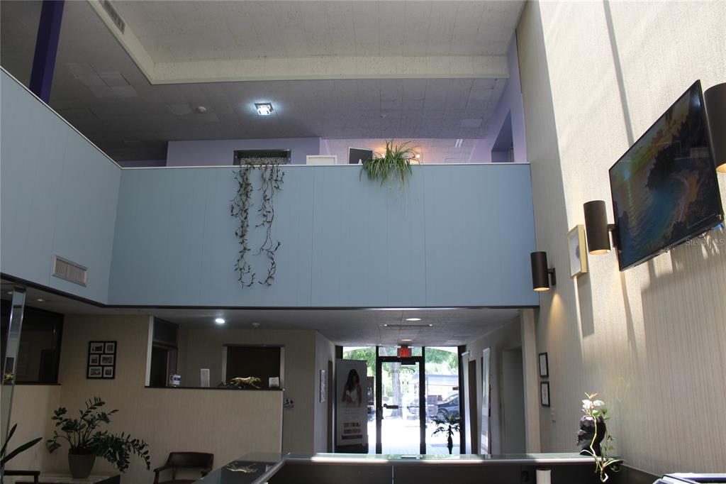 A high-ceilinged lobby features a reception desk, a mezzanine level, and a wall-mounted television — 1253/1255 PARK STREET, CLEARWATER, FL