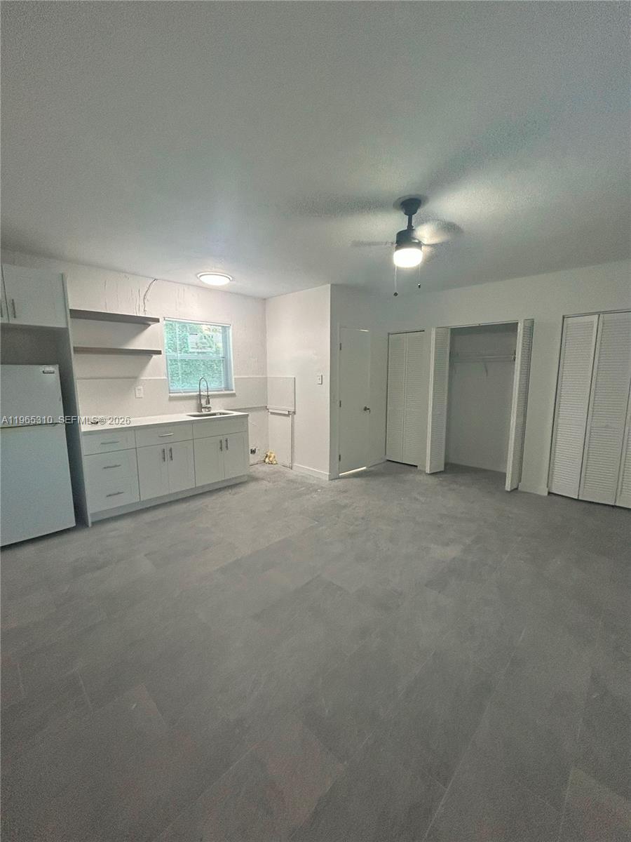 This kitchen features white cabinets, open shelving, a window, and light-colored tile flooring — 1220-1222 NE 110th Ter, Miami FL 33161, MIAMI, FL