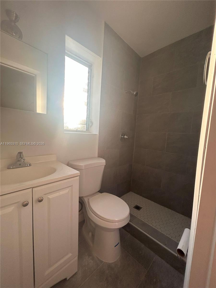 A bathroom features a white vanity, a toilet, and a walk-in shower with gray tiling — 1220-1222 NE 110th Ter, Miami FL 33161, MIAMI, FL