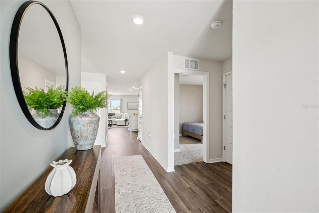 A hallway with wood-look flooring leads to a living area and a bedroom doorway — 4513 FAITH DRIVE, LAKE WALES, FL