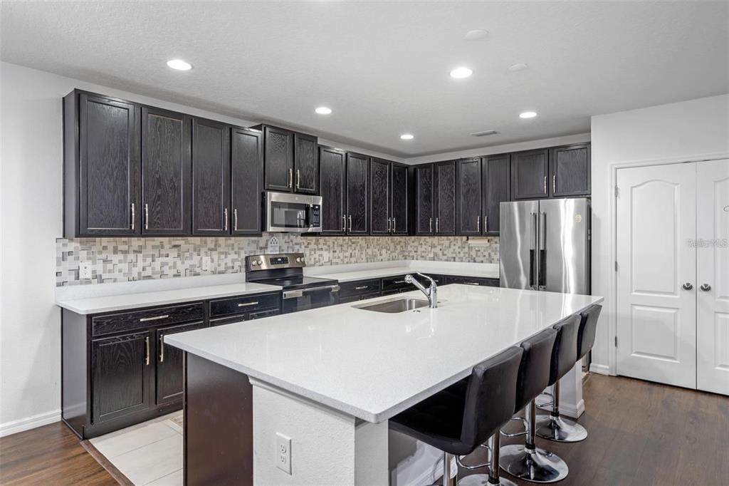 A kitchen with dark wood cabinets, white countertops, a large island, and stainless steel appliances — 189 LUXMORE ROAD, GROVELAND, FL