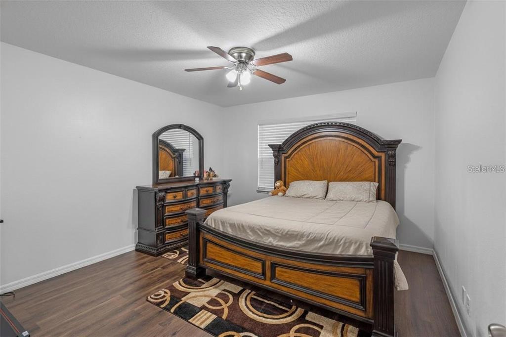 A bedroom features a large wooden bed frame, a matching dresser with mirror, and flooring — 189 LUXMORE ROAD, GROVELAND, FL