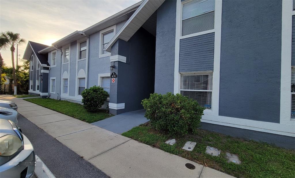 A multi-story apartment building exterior with blue stucco walls, white trim, and a sidewalk — 4136 PERSHING POINTE PLACE UNIT 5, ORLANDO, FL