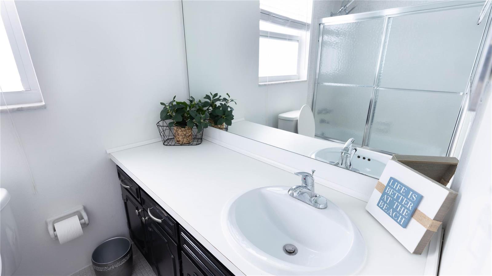 A bathroom features a white vanity with a black cabinet, a sink, and a mirror — 3100 N Course Lane # 510, Pompano Beach FL 33069, POMPANO BEACH, FL