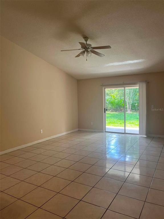 A living room features light-colored tile flooring, a ceiling fan, and sliding glass patio doors — 6 PLEASANT LANE, PALM COAST, FL