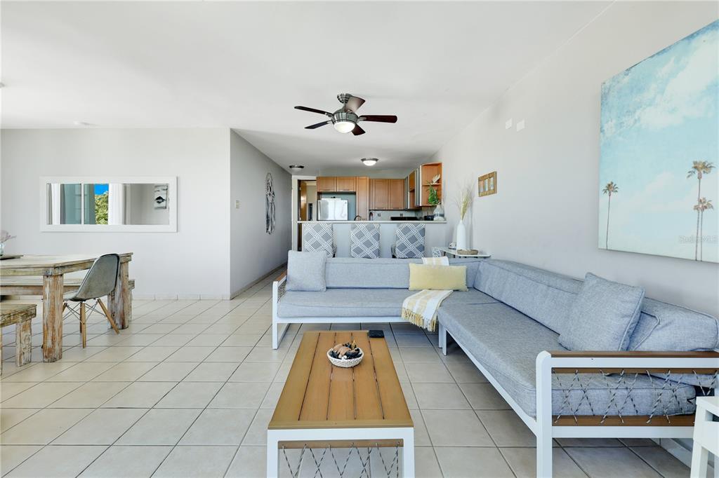 A living room with tile floors, a gray sectional sofa, and an open kitchen — 115 115 UNIT 401, RINCON, PR