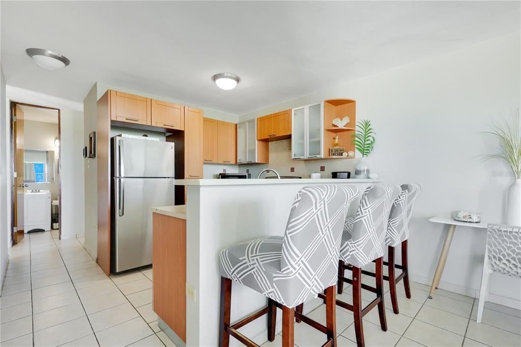 A kitchen features a stainless steel refrigerator, light wood cabinets, and a breakfast bar — 115 115 UNIT 401, RINCON, PR
