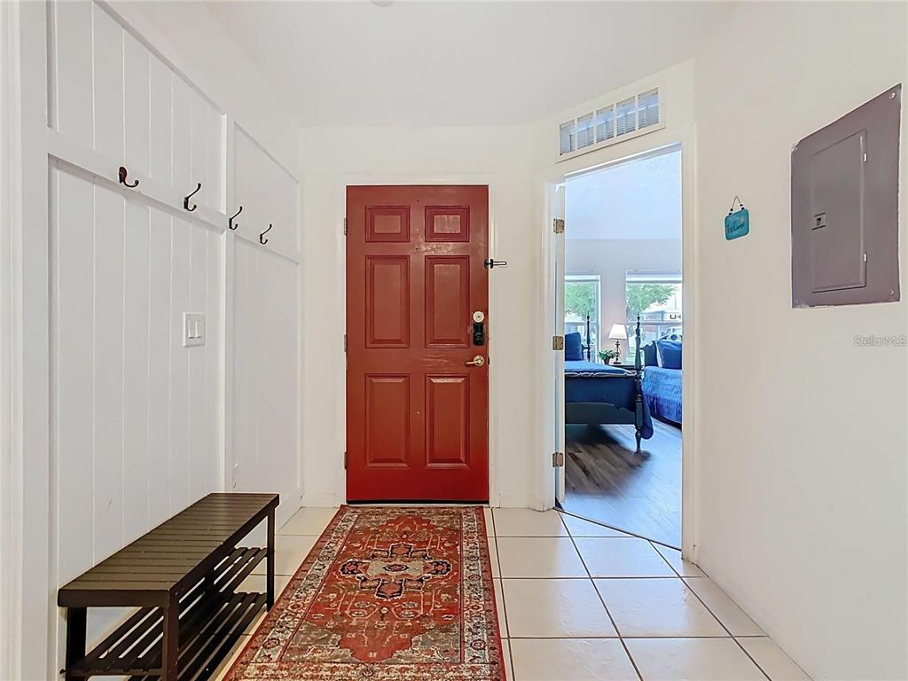 An entryway features a red front door, a white coat rack wall, and a tiled floor — 2810 CLUB CORTILE CIRCLE UNIT A, KISSIMMEE, FL