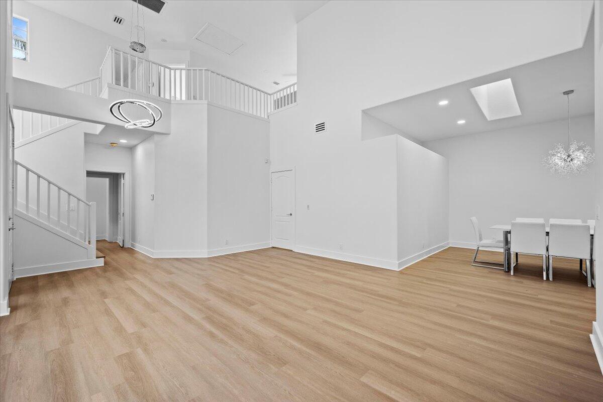 A bright, open-concept living and dining area features white walls, light wood flooring, and stairs — 10375 Osprey Trace, West Palm Beach FL 33412, WEST PALM BEACH, FL
