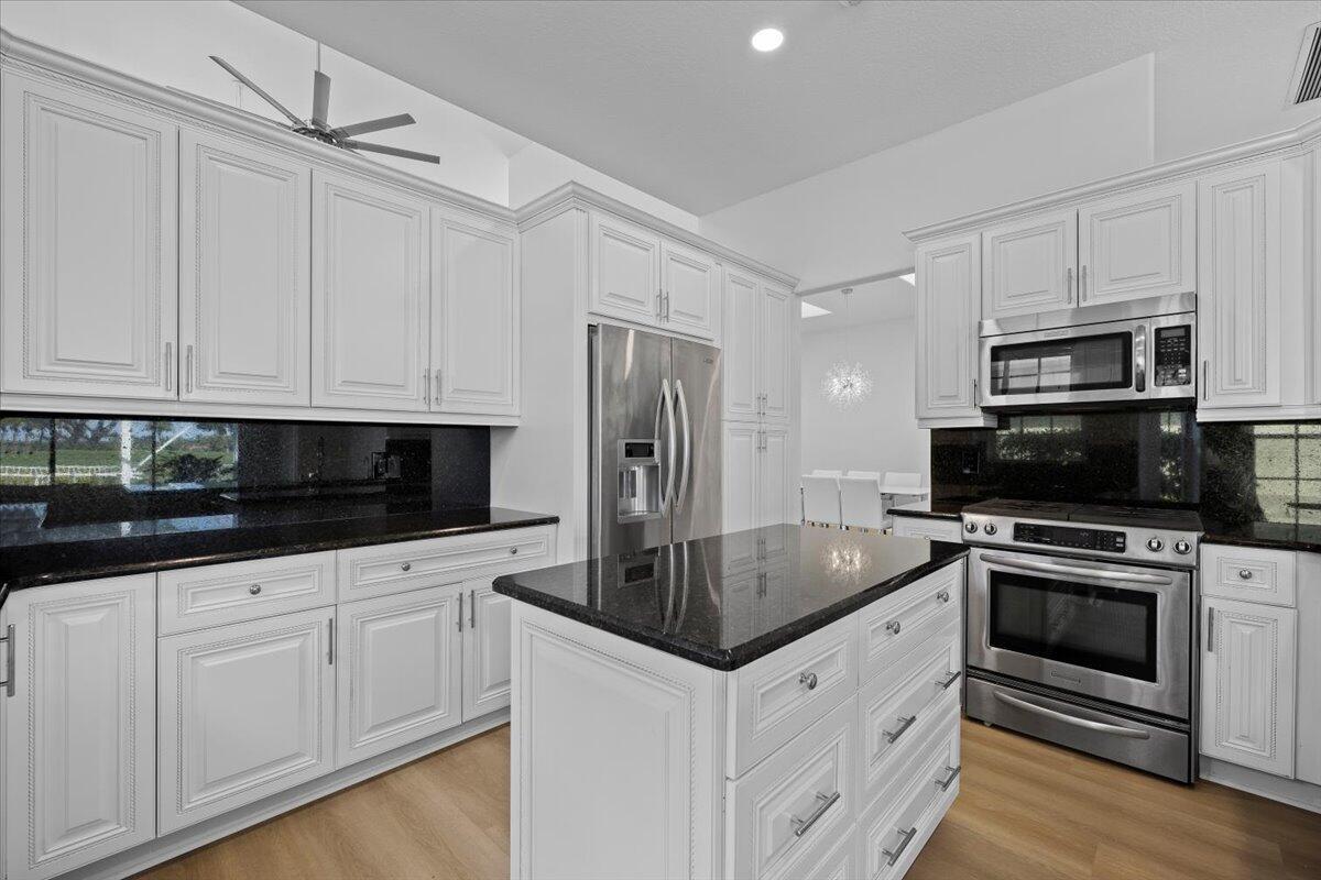 A kitchen with white cabinets, black granite countertops, stainless steel appliances, and a central island — 10375 Osprey Trace, West Palm Beach FL 33412, WEST PALM BEACH, FL