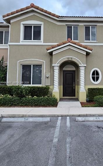 A two-story townhouse exterior with a covered entryway, white columns, and a small oval window — 1015 SE 24th Ter # 1015, Homestead FL 33035, HOMESTEAD, FL