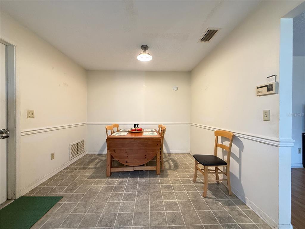 A dining area features a wooden drop-leaf table, chairs, and tiled flooring — 622 GOODWIN AVENUE, NEW SMYRNA BEACH, FL