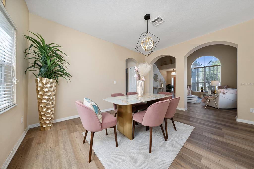 A dining room features a marble-topped table, pink velvet chairs, and a geometric pendant light — 2764 PATRICIAN CIRCLE, KISSIMMEE, FL