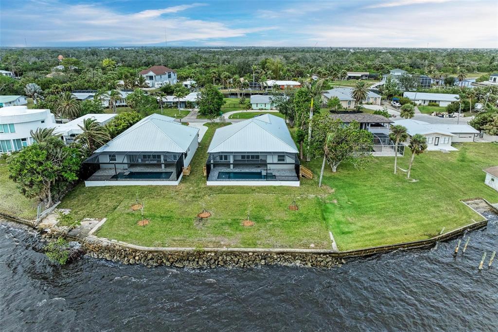 An aerial view shows two waterfront houses with screened-in pools and a shared grassy lawn — 112 NORTHSHORE TERRACE, PUNTA GORDA, FL
