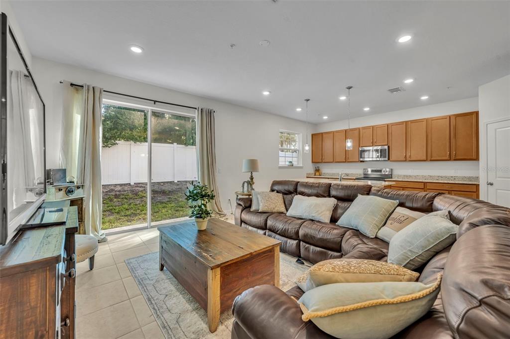 A living room with a brown leather sectional, wooden coffee table, and an open kitchen — 986 GRAND WILDMERE COVE, LONGWOOD, FL
