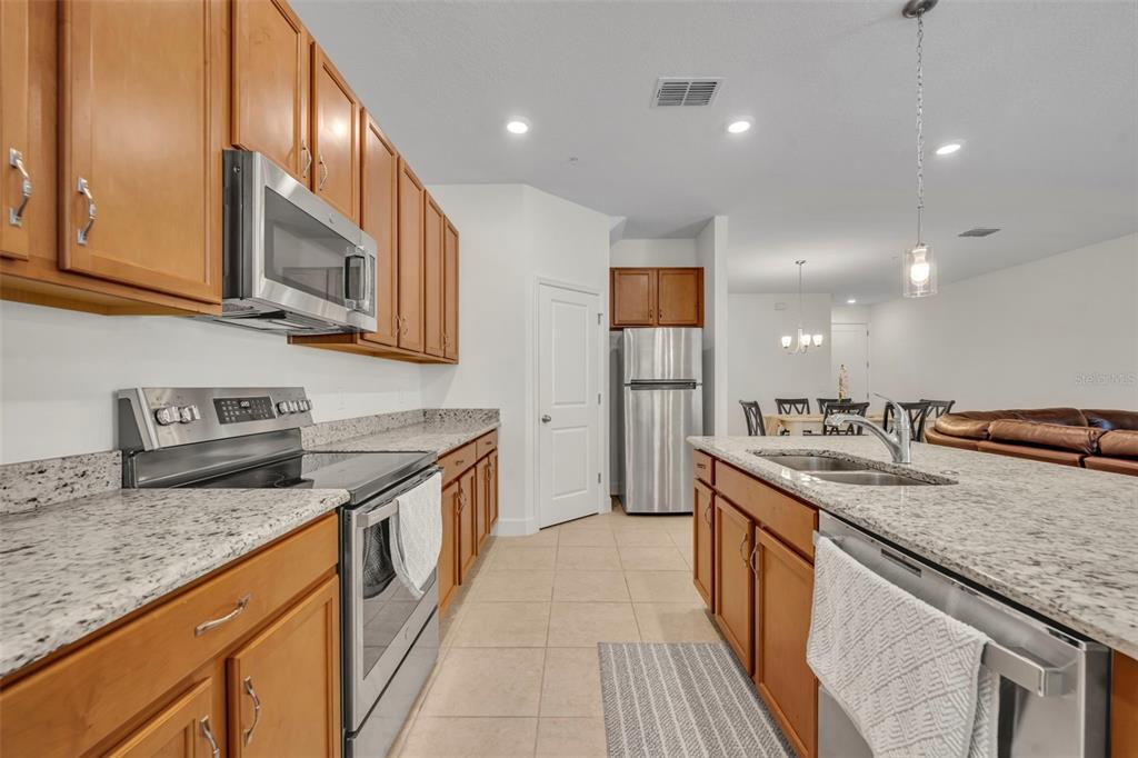 A kitchen features wood cabinets, granite countertops, stainless steel appliances, and an island — 986 GRAND WILDMERE COVE, LONGWOOD, FL