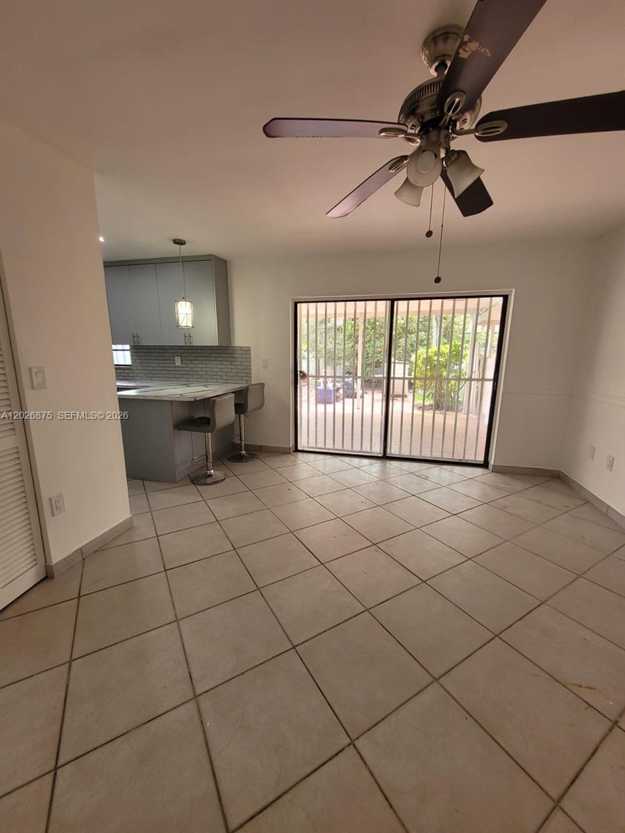 A kitchen with gray cabinets and a breakfast bar opens to a tiled dining area — 2438 SW 109th Ct, Miami FL 33165, MIAMI, FL