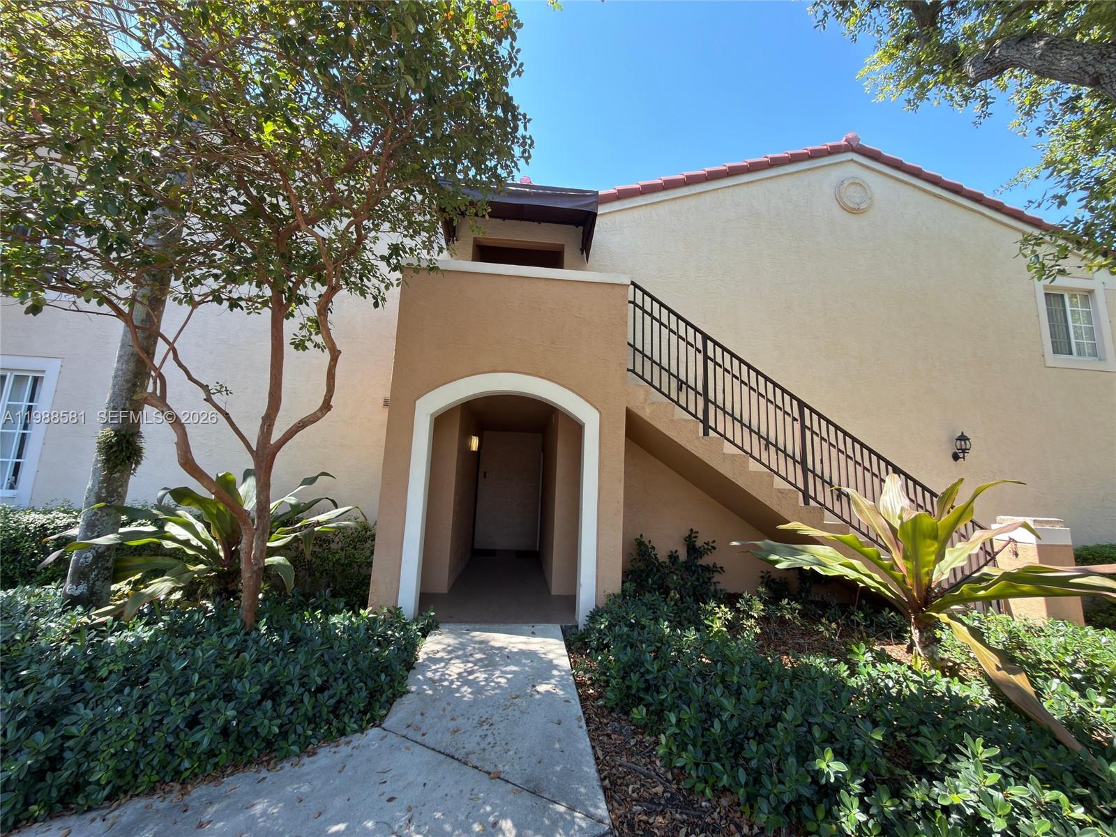 An exterior view shows a tan building with a staircase leading to an upper entrance — 2173 Renaissance Blvd # 101, Miramar FL 33025, MIRAMAR, FL