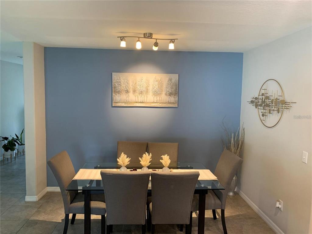 A dining room features a glass-top table, six grey chairs, and a blue accent wall — 10460 CARLOWAY HILLS DRIVE, WIMAUMA, FL