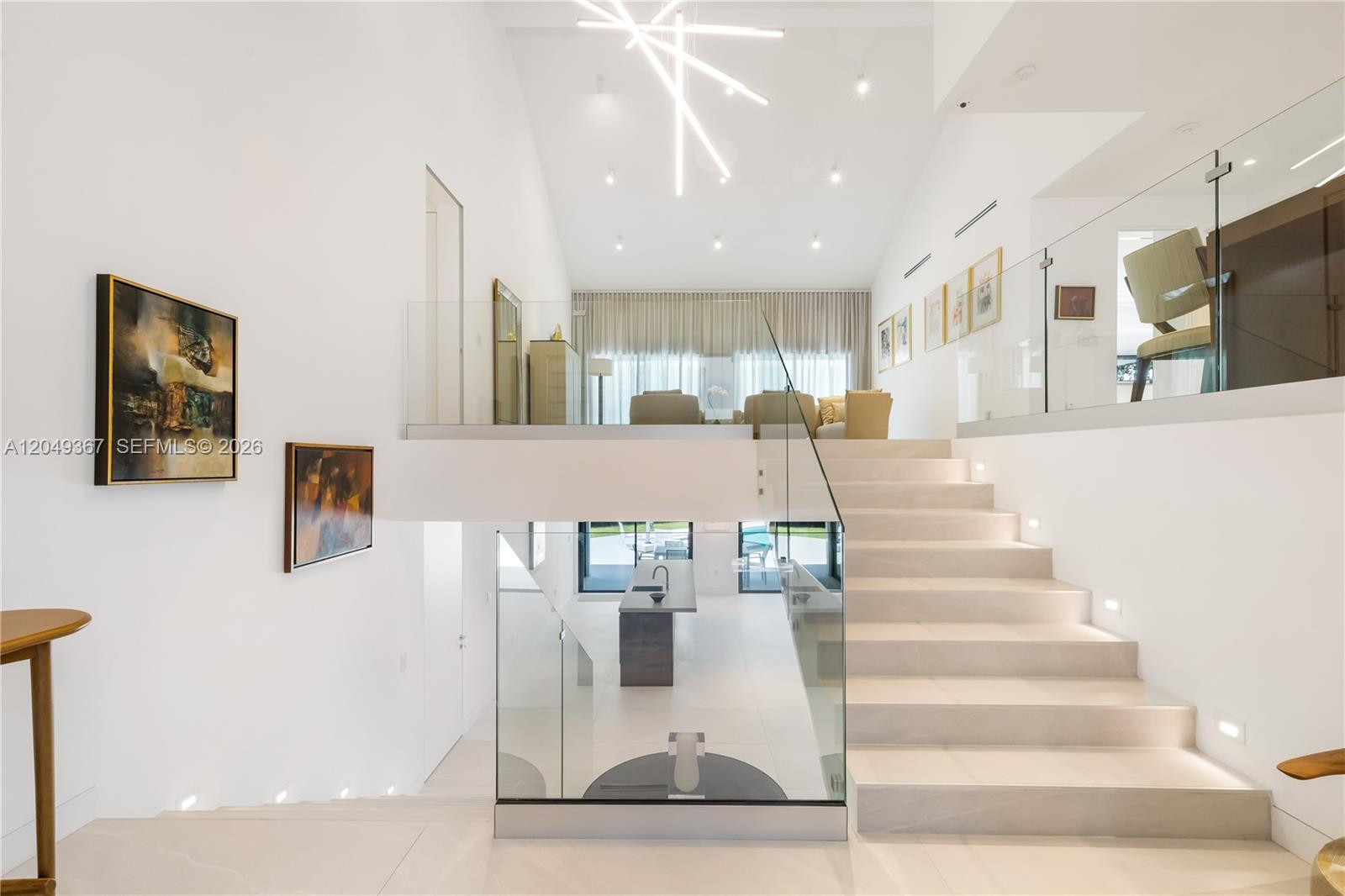 A modern, multi-level interior features a glass-railed staircase leading to an elevated living area — 7180 E Lago Dr, Coral Gables FL 33143, CORAL GABLES, FL