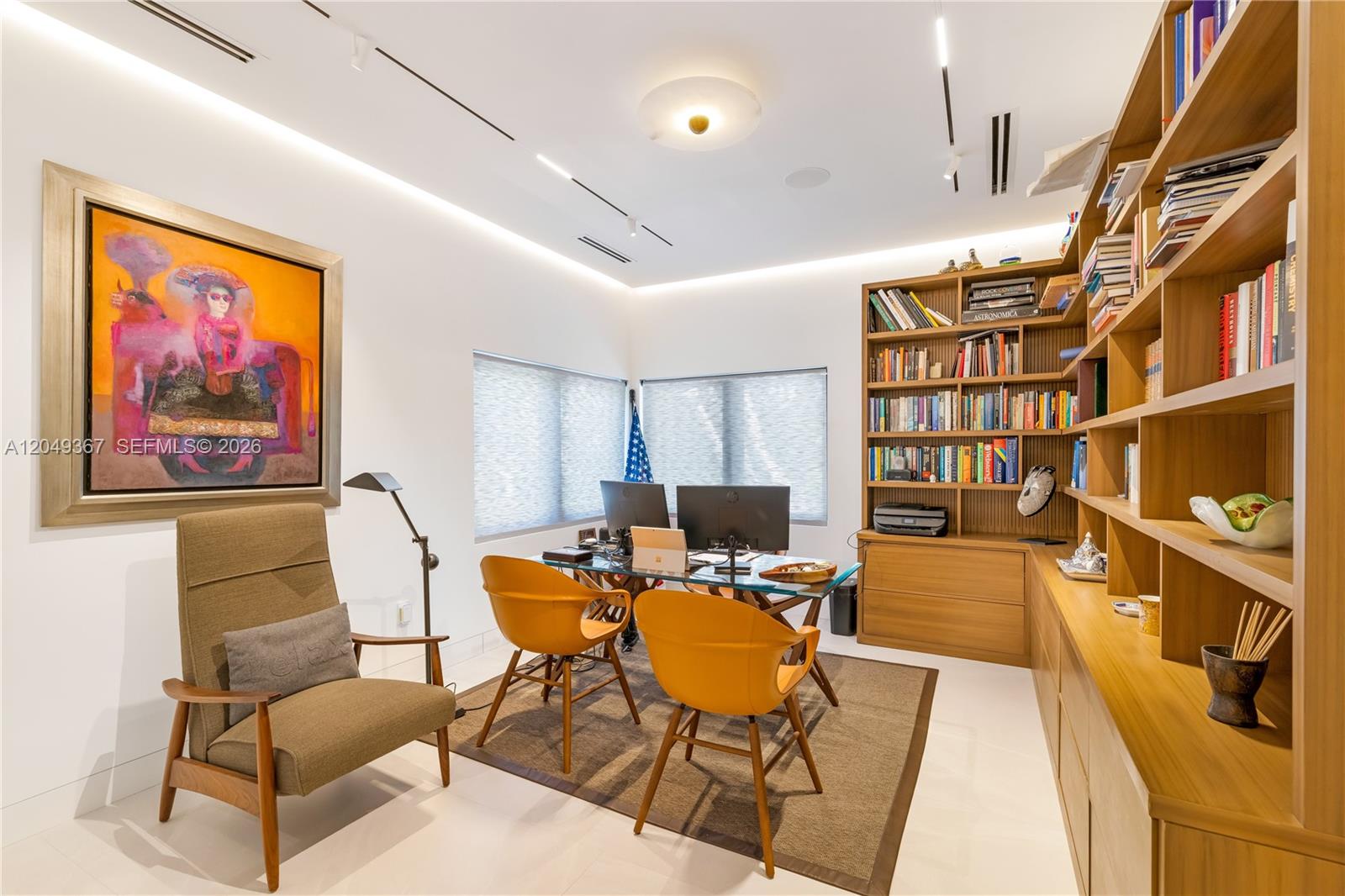 A home office features a desk, two orange chairs, a bookshelf, and a large painting — 7180 E Lago Dr, Coral Gables FL 33143, CORAL GABLES, FL